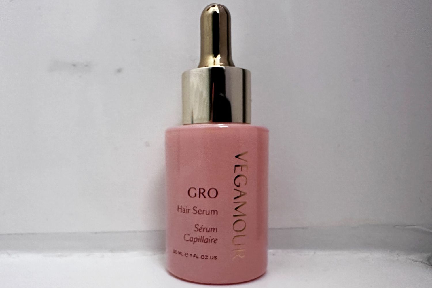 A bottle of Vegamour GRO Hair Serum in front of a gray wall