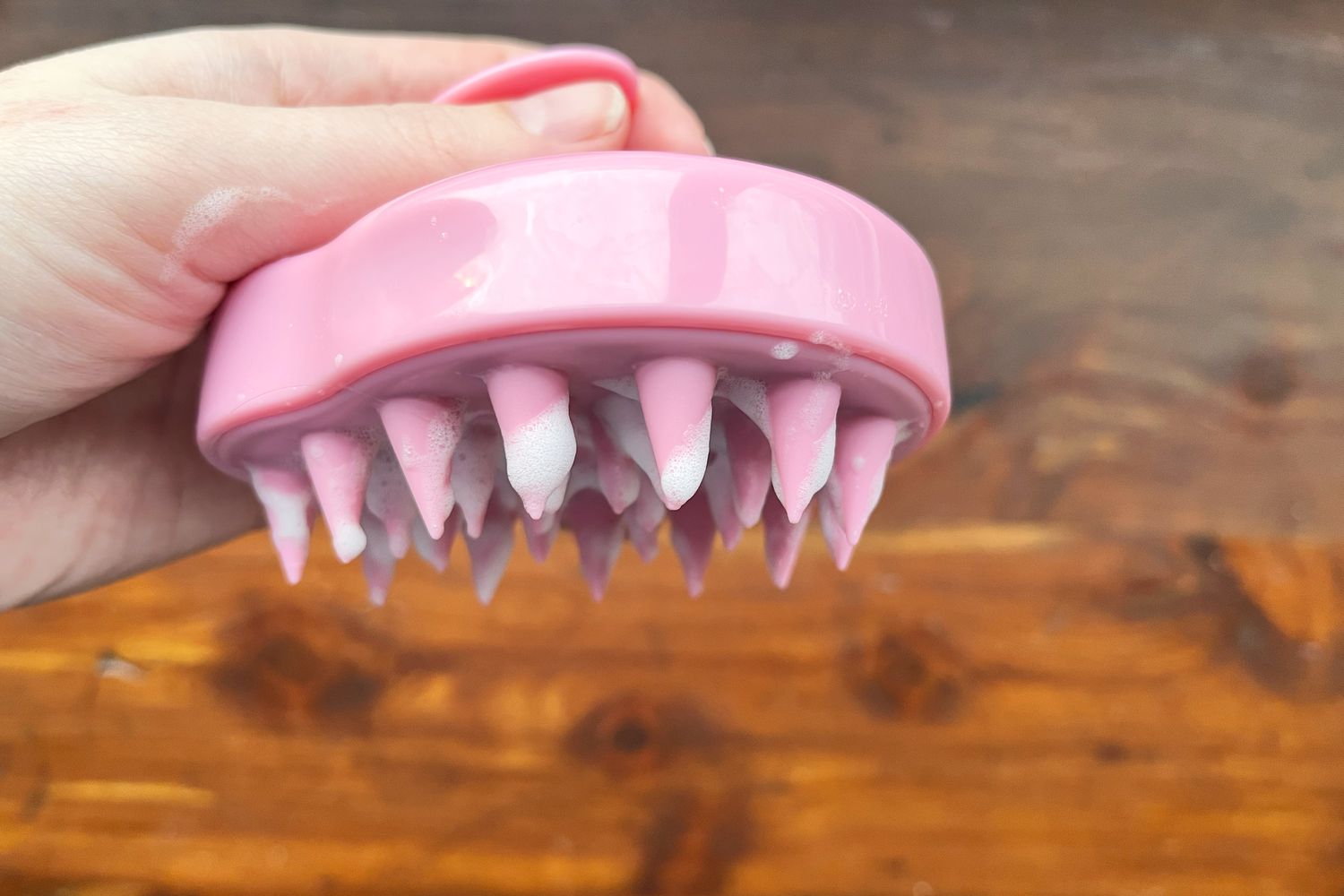 Hand holding pink Maxsoft Hair Scalp Massager covered in suds