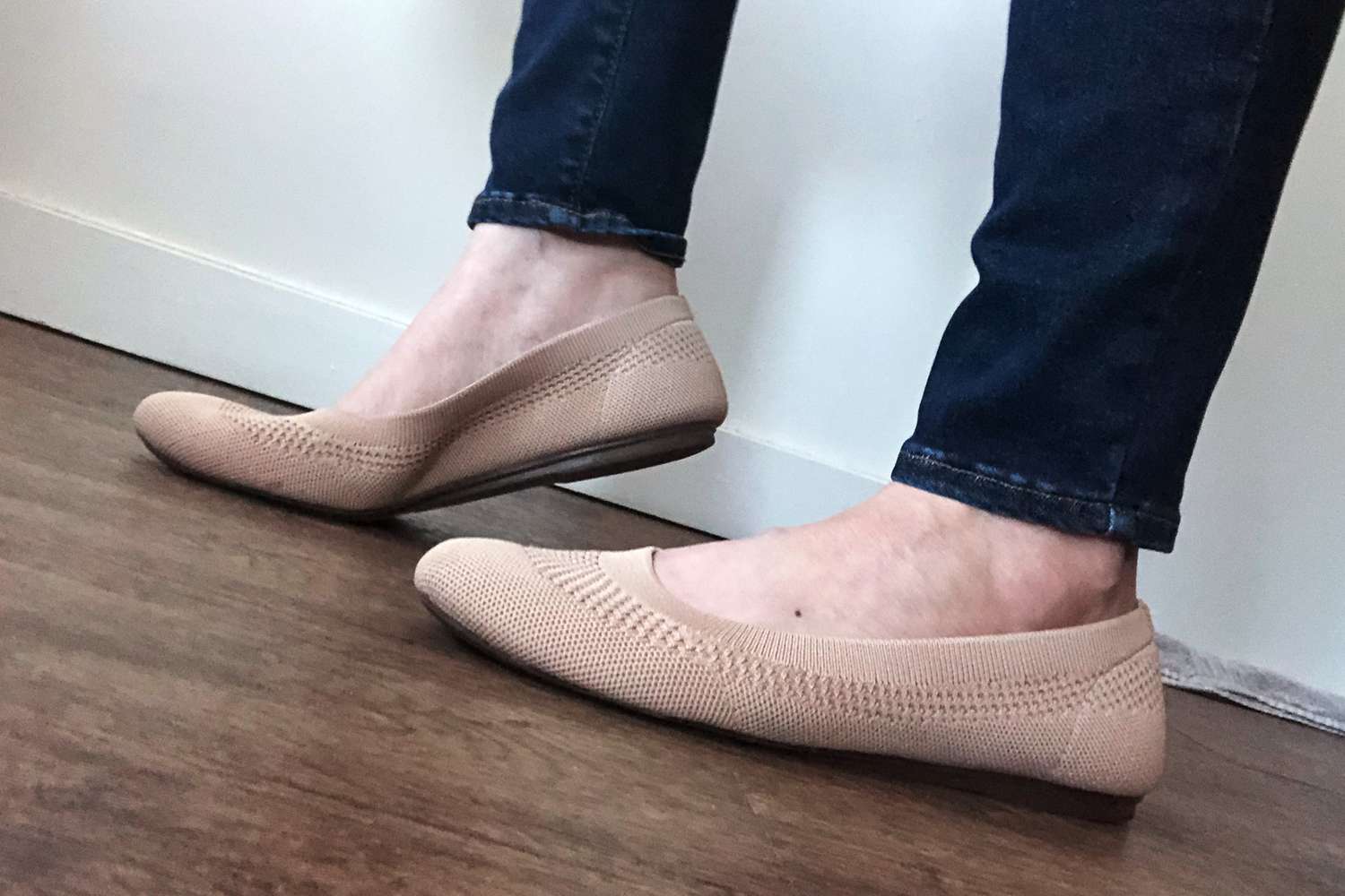 Feet wearing Frank Mully Round Toe Ballet Flats on a wood floor