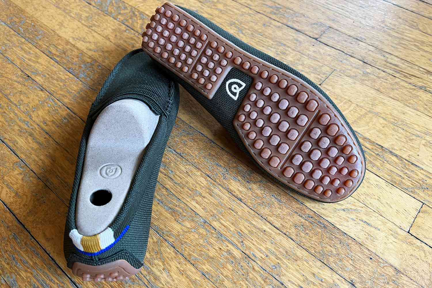 Rothy’s The Driver loafers displayed on a wood floor with one shoe flipped to show bottom tread