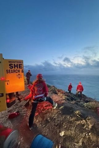 Rescue workers near a yellow search and rescue truck on rocky Big Sur coastline during sunset Monterey County Sheriff's Office