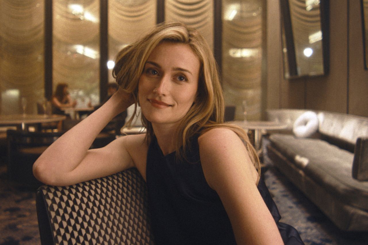 A person seated in a room with patterned chairs and decorative draped walls looking at the camera casually Sarah Pidgeon as Carolyn Bessette KennedyCredit: FX