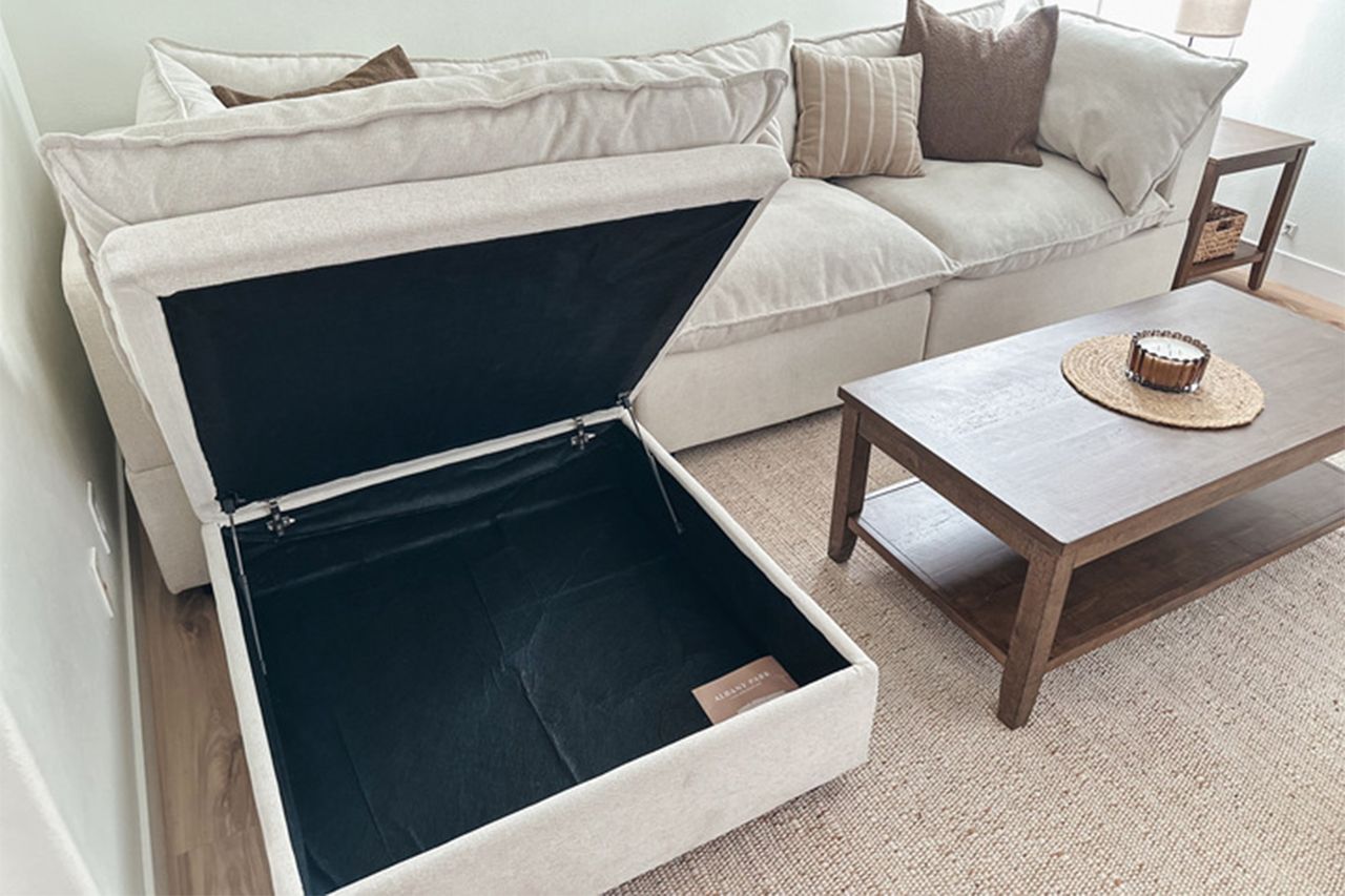 Open storage ottoman beside a couch and coffee table People