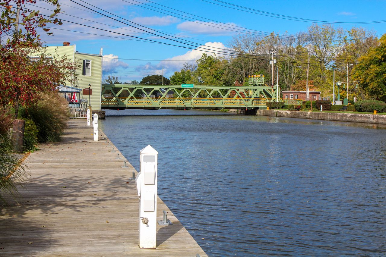 A canal with a green bridge a wooden walkway and nearby vegetation Erie Canal in New YorkCredit: Getty