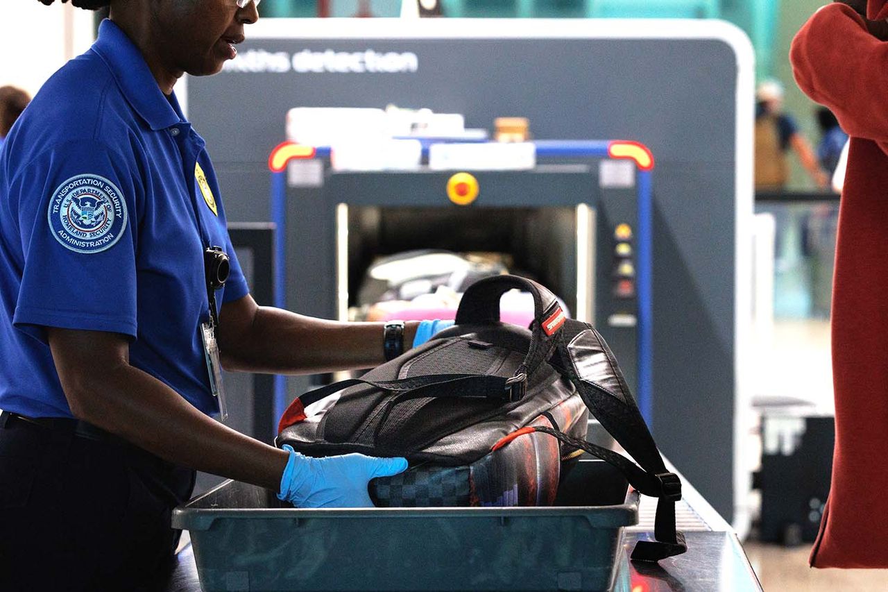 A Transportation Security Administration (TSA) agent assists travelers as they place their luggage onto a scanner belt at the TSA security checkpoint at Dallas Love Field Airport (DAL) in Dallas, Texas, US, on Thursday, Aug. 28, 2025. A TSA agent at an airport.Credit: Shelby Tauber/Bloomberg via Getty