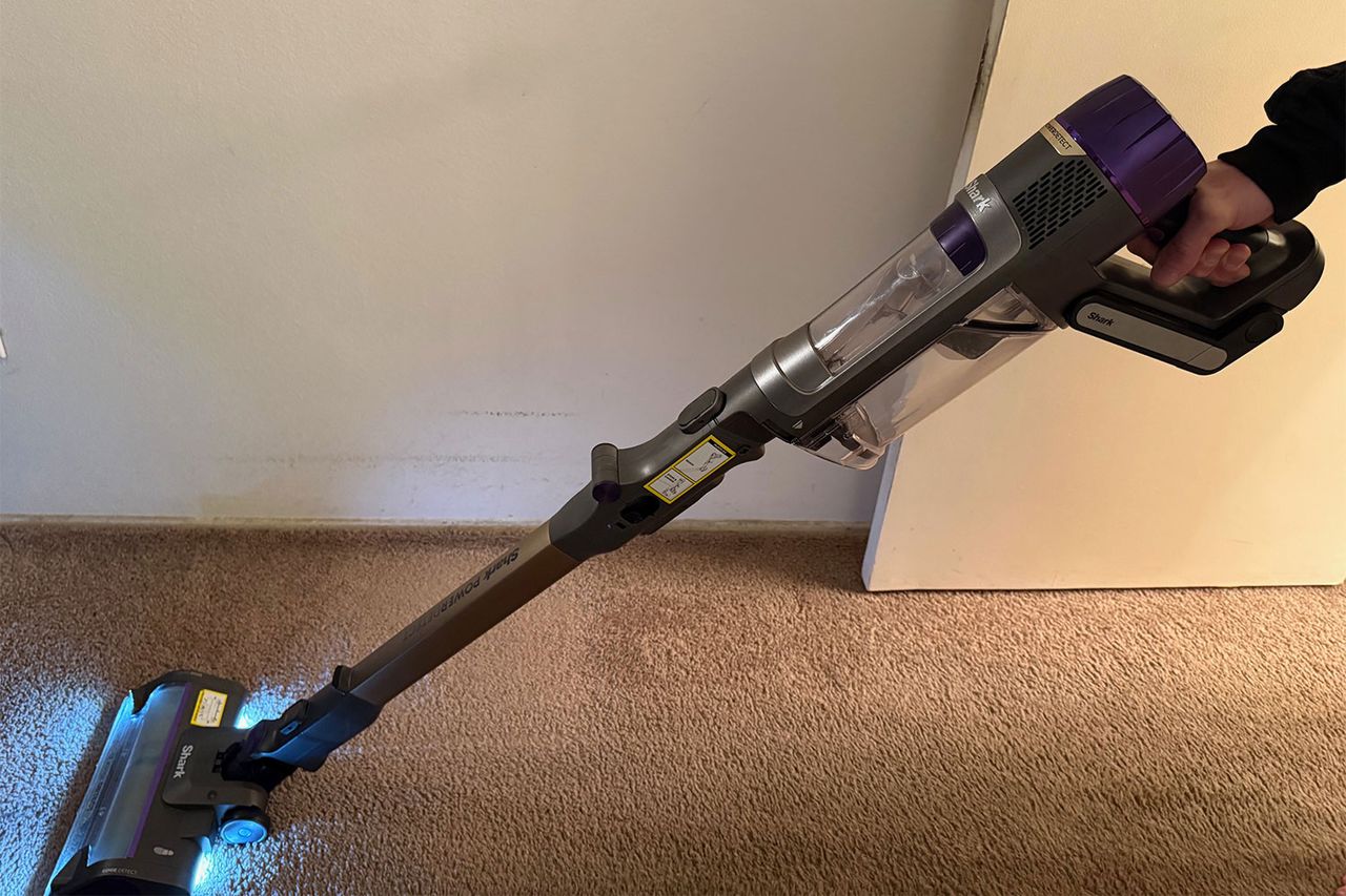 A hand using a cordless vacuum cleaner on a carpeted floor Credit: People