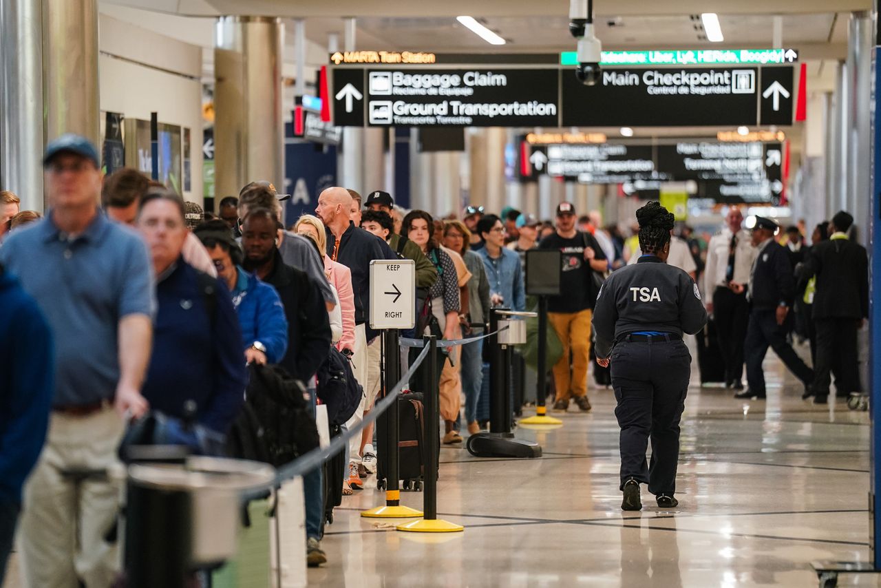 A Transportation Security Administration (TSA) agent walks past travelers waiting in line at a checkpoint at Hartsfield-Jackson Atlanta International Airport (ATL) in Atlanta, Georgia, US, on Monday, March 23, 2026. President Donald Trump said he did not want Immigration and Customs Enforcement agents detailed to airports to wear masks as they assist with security screenings, even as he continued to support officers using face coverings during deportation operations. Photographer Travelers waiting in long lines at Hartsfield-Jackson Atlanta International Airport (ATL) on Monday, March 23, 2026Credit: Elijah Nouvelage/Bloomberg via Getty Images