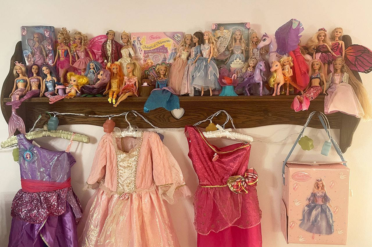 A shelf displaying dolls with various dresses hanging below The items found in the atticCredit: Molley Delaney