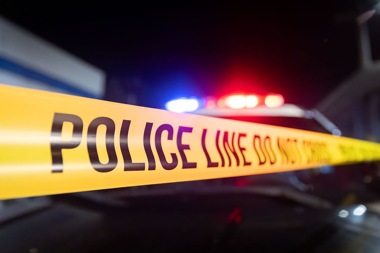 Nighttime shot of unfurled police tape next to flashing lights from a police car. Stock photo of police tapeCredit: Getty