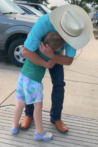 An adult wearing a cowboy hat hugging a child outside near a parked car Ryan Ainsworth meeting PennyCredit: Paula White/TikTok