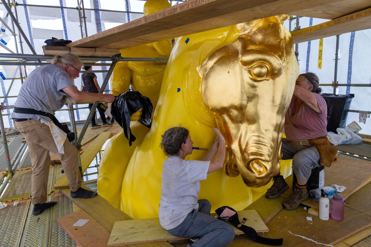 Workers restoring a large goldcolored horse statue at a construction siteCredit: truth social