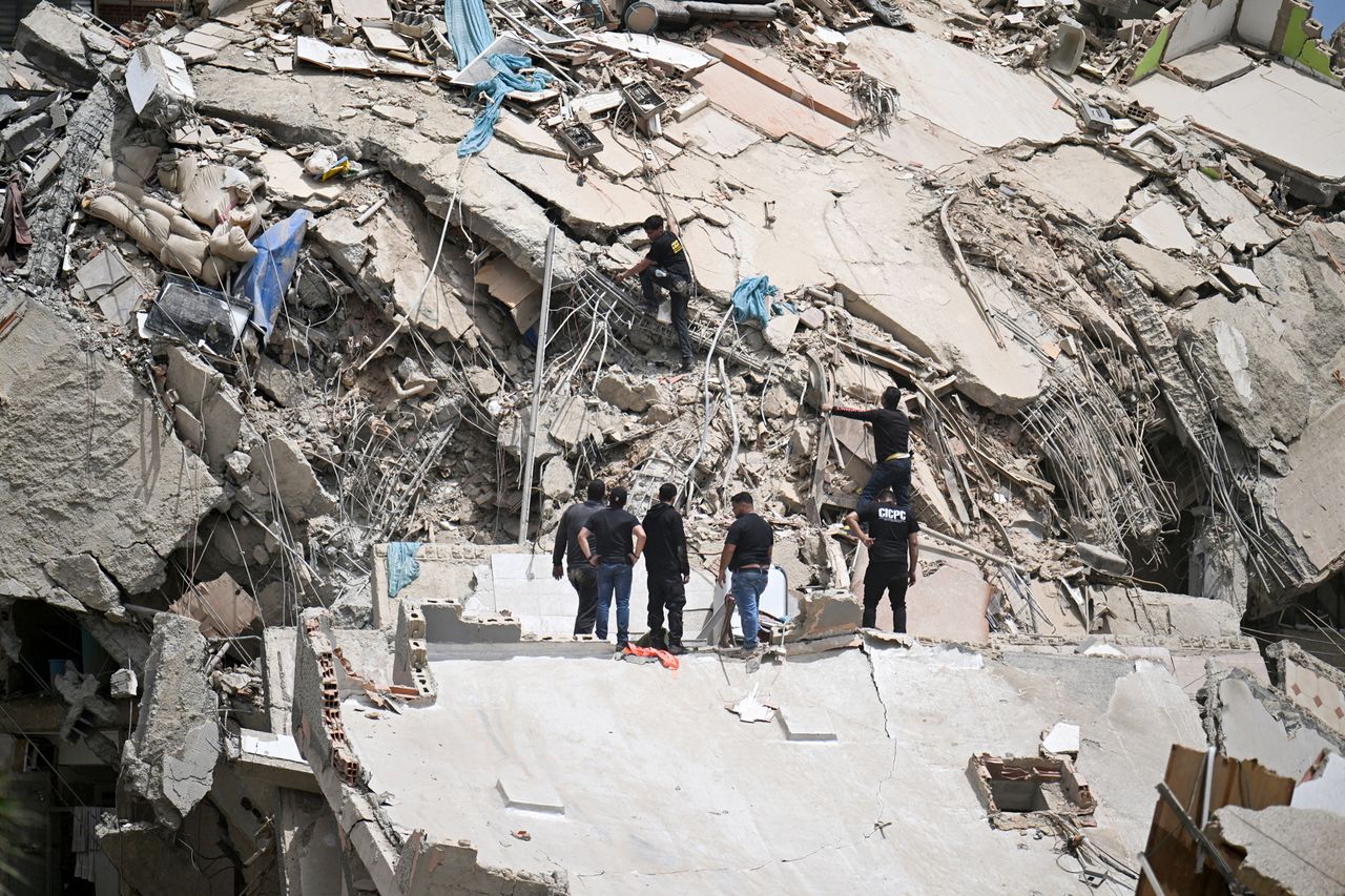 Rescue workers stand on the slab of a collapsed building amid twisted rebar and debris during search operations following an earthquake in Catia La Mar, La Guaira state on June 25Credit: Juan BARRETO / AFP via Getty