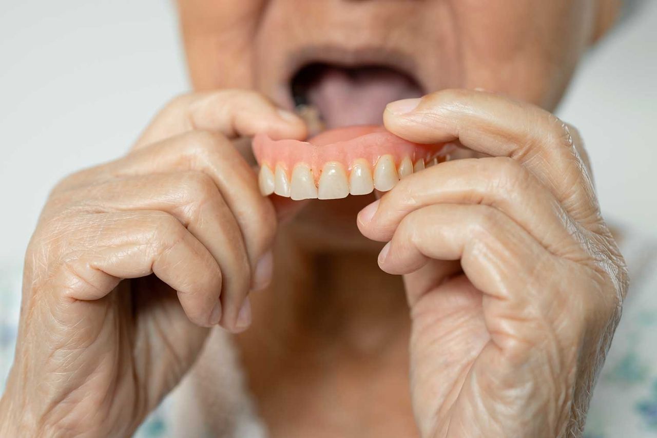 A woman holding dentures.Credit: Getty