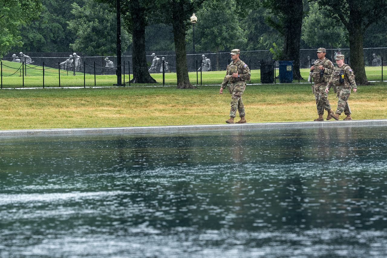 Three uniformed individuals walking along a path near a body of water with a fenced area and trees in the background National Guard troops near the Lincoln Memorial Reflecting Pool on June 23Credit: Ken Cedeno / AFP via Getty