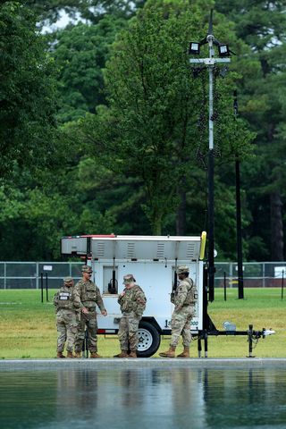 A group of soldiers standing near a mobile equipment unit in an outdoor area National Guard troops near a mobile camera trailer on June 23Credit: Chip Somodevilla/Getty I