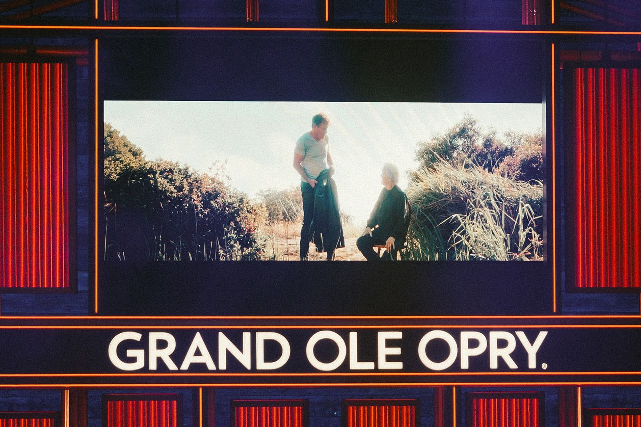 A video screen displaying individuals in a rural setting projected at the Grand Ole Opry Dennis Quaid and Kris Kristofferson on-screen at the Grand Ole OpryCredit: Caleb Herring