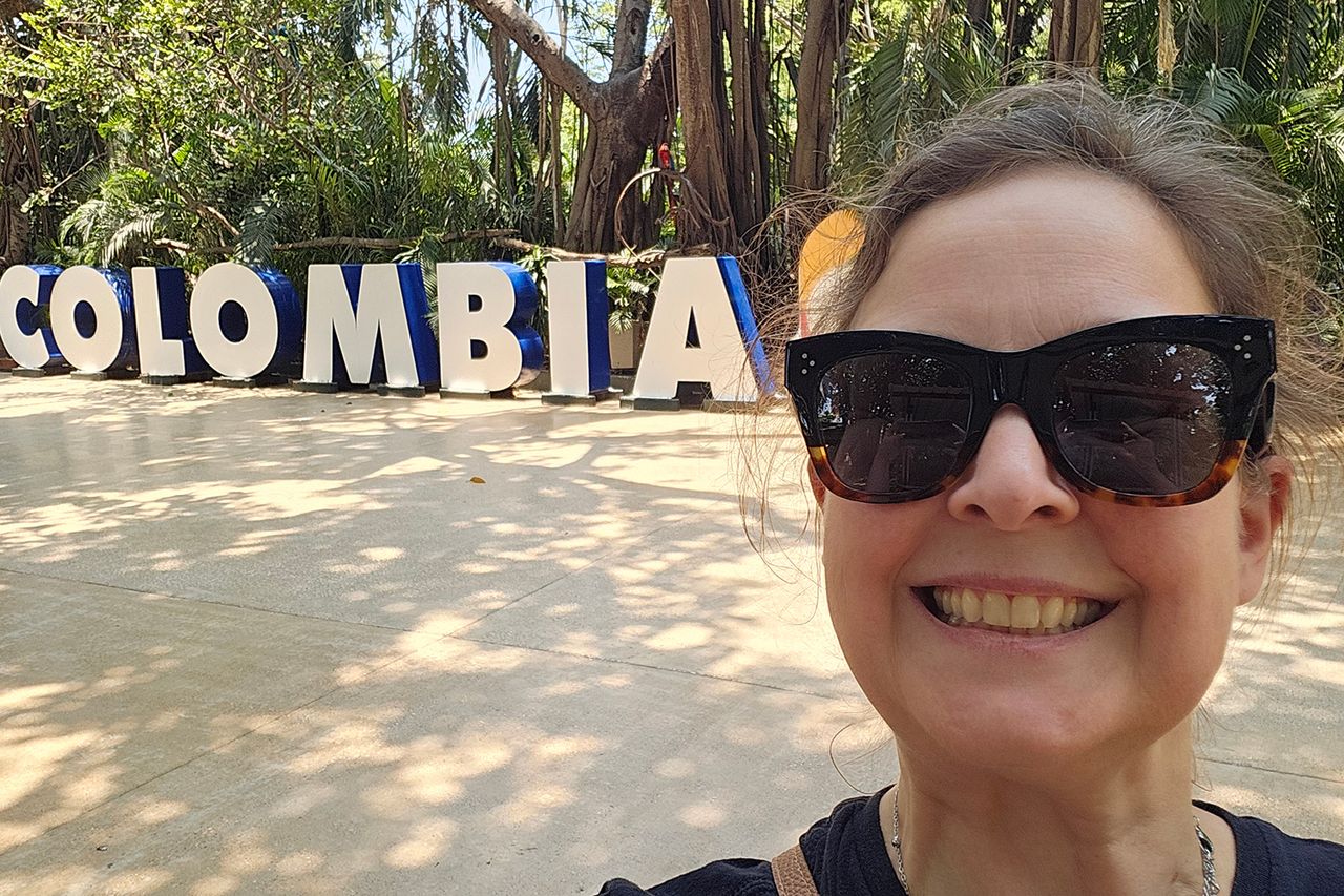 Person smiling in front of Colombia signage in a lush outdoor setting Libby Rome in ColombiaCredit: Courtesy of Libby Rome