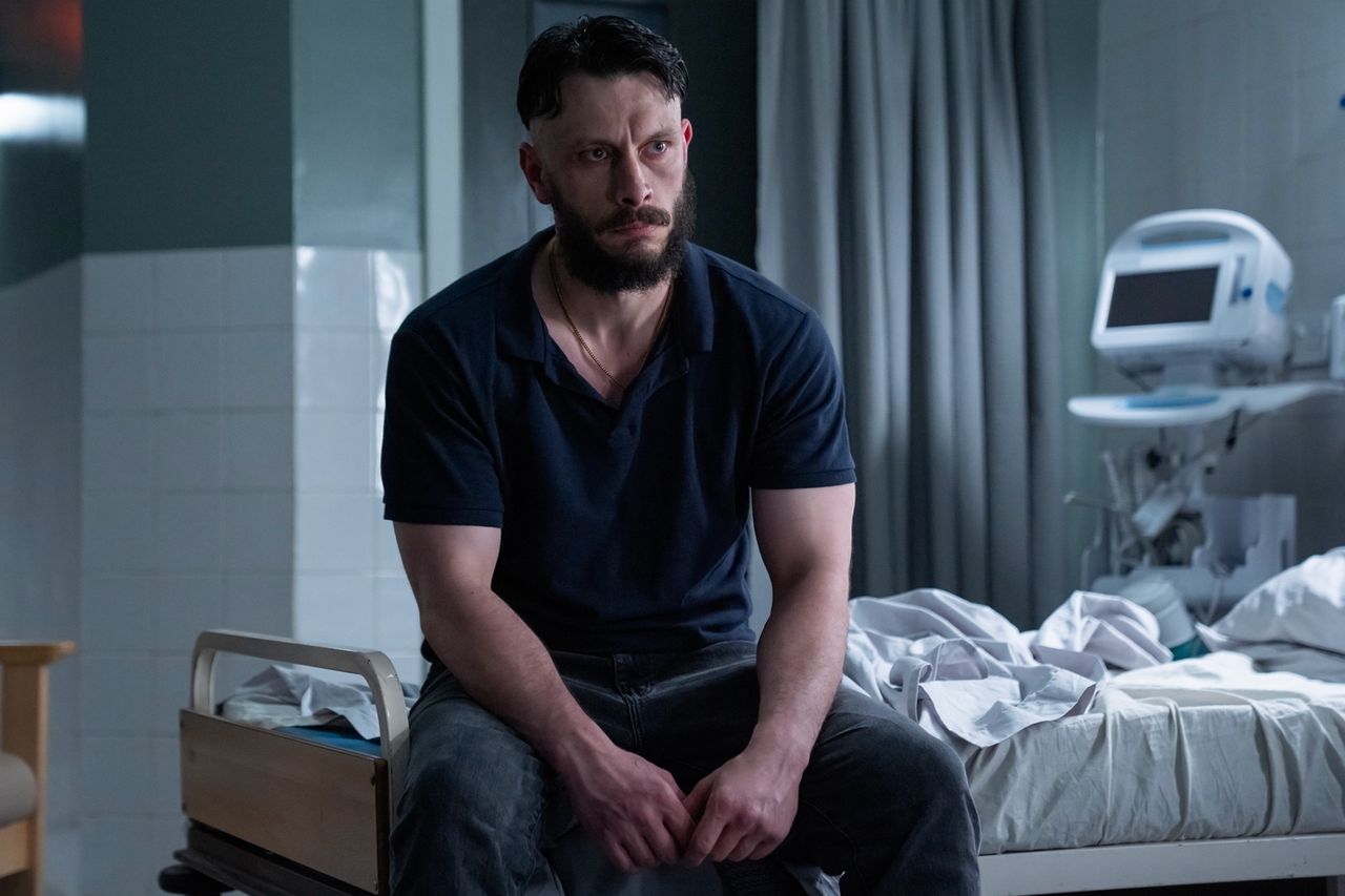 A bearded man sitting on the edge of a hospital bed in a dimly lit room with medical equipment and a chair nearby Richard Gadd in ‘Half Man.’Credit: HBO
