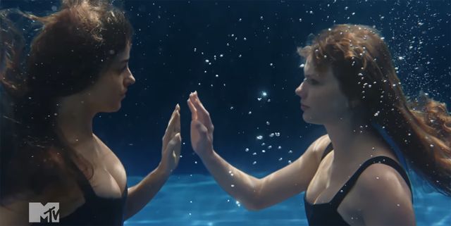 Two women underwater facing each other and touching hands with hair floating in the water Dakota Johnson and Taylor Swift in “Patient Zero” music videoCredit: mtv